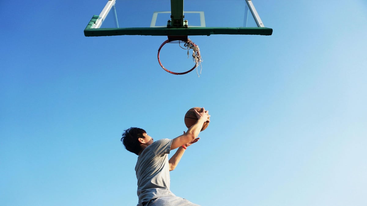 En person gör en slamdunk i en basketmatch på 1X2.