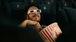 En person kollar på en film med Stellan Skarsgård i en biograf och äter popcorn.